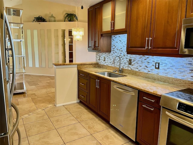 kitchen with pendant lighting, sink, decorative backsplash, stainless steel appliances, and light stone countertops