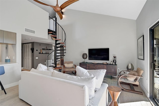 living room with ceiling fan, high vaulted ceiling, and light hardwood / wood-style floors