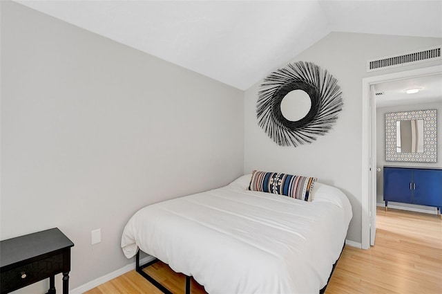 bedroom with hardwood / wood-style flooring and lofted ceiling