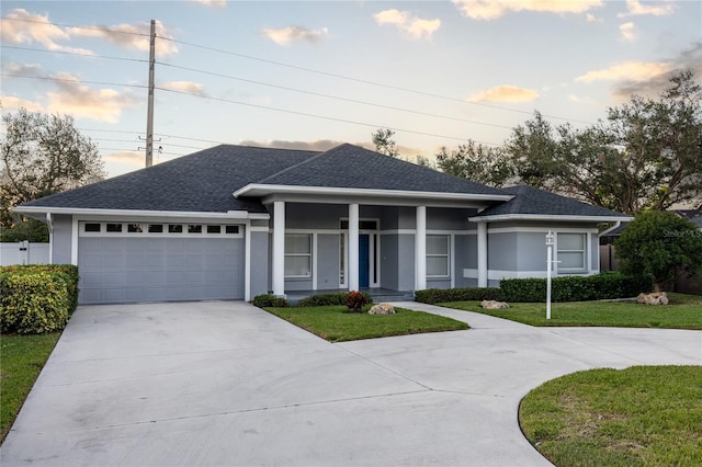 view of front of house with a porch, a yard, and a garage