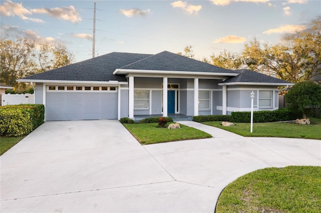 view of front of property with a porch, a garage, and a front lawn