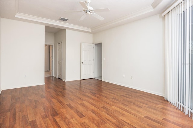 unfurnished bedroom with a tray ceiling, ceiling fan, crown molding, and dark hardwood / wood-style floors