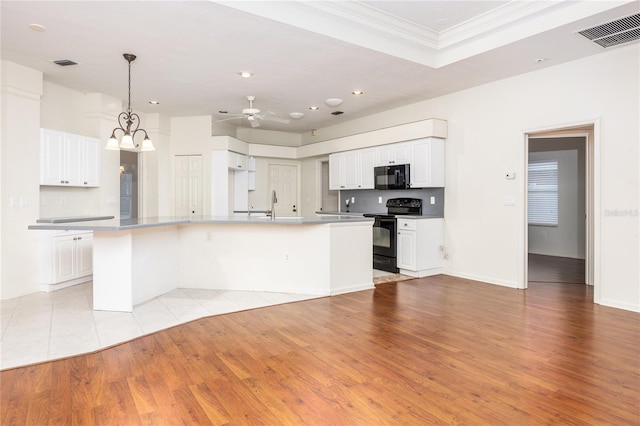 kitchen featuring light wood-type flooring, crown molding, black appliances, a center island with sink, and white cabinetry