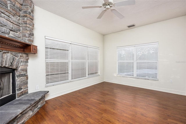 unfurnished living room featuring ceiling fan, a fireplace, and dark wood-type flooring