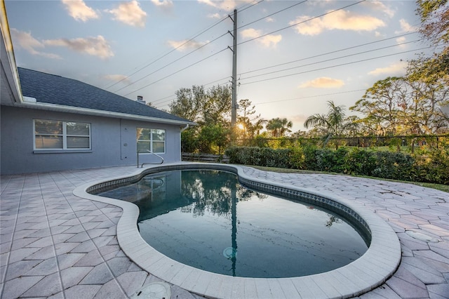 pool at dusk with a patio area