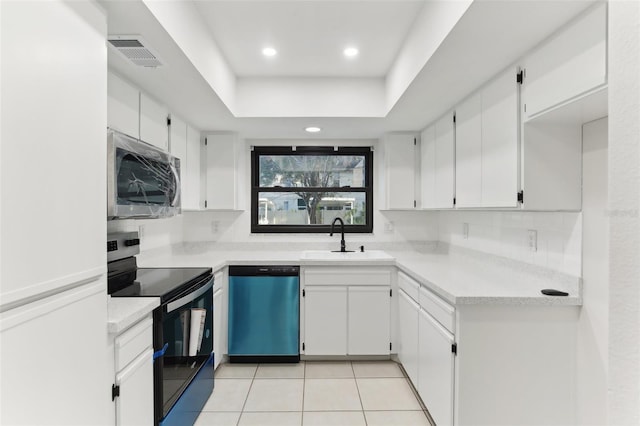 kitchen with a tray ceiling, sink, white cabinets, and appliances with stainless steel finishes