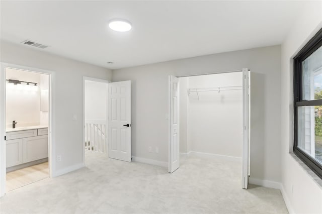 unfurnished bedroom featuring connected bathroom, light carpet, a closet, and sink