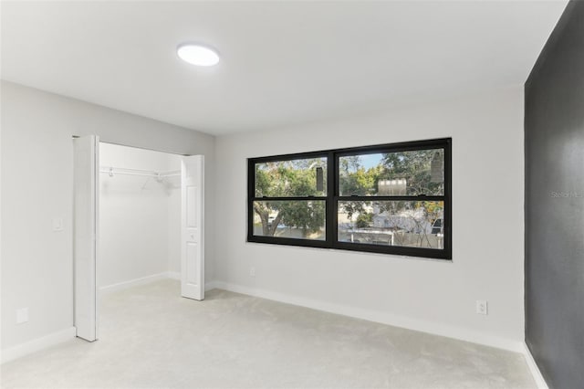 unfurnished bedroom featuring light carpet and a closet