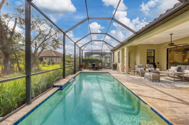 view of pool with an outdoor living space, glass enclosure, ceiling fan, and a patio area