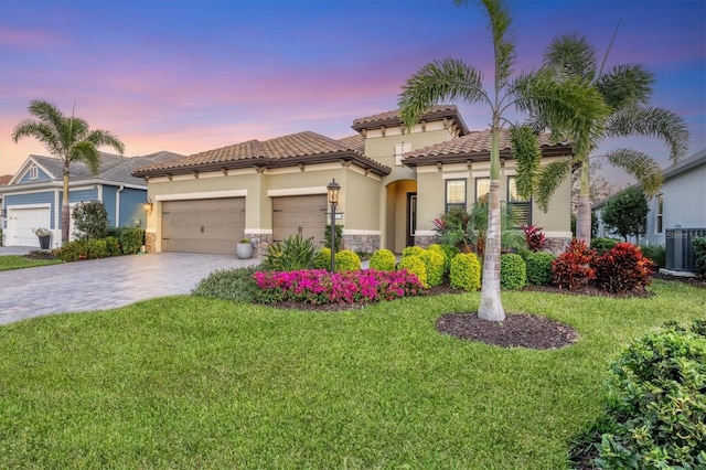 mediterranean / spanish-style home with a yard, central AC unit, and a garage