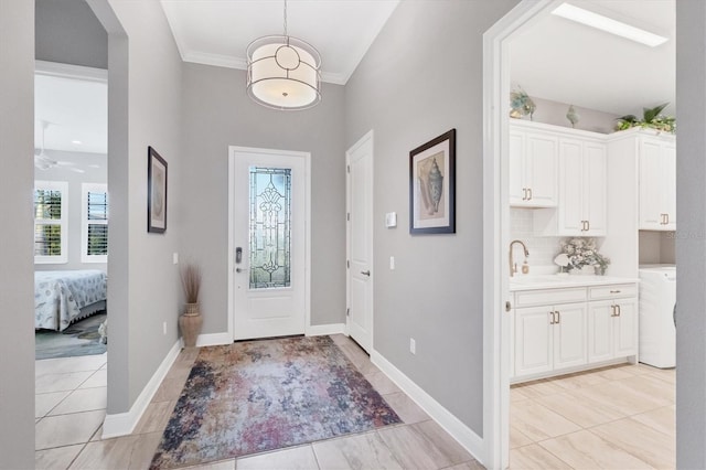 foyer entrance with sink, crown molding, and washer / clothes dryer