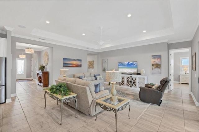 living room with a tray ceiling, ceiling fan, and crown molding