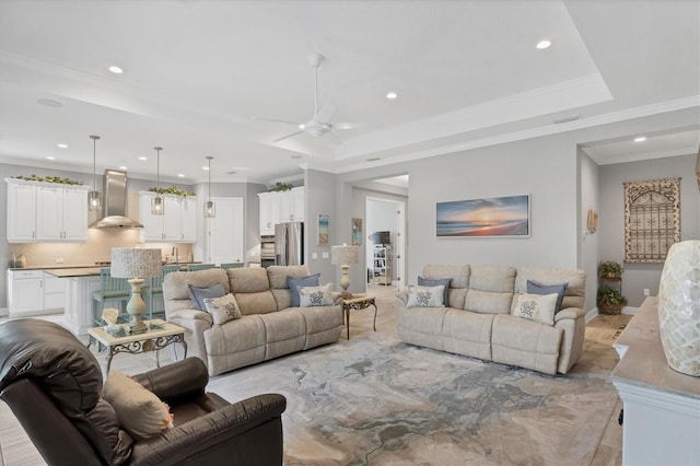 living room featuring ceiling fan, a raised ceiling, and crown molding