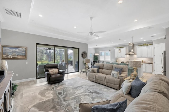 tiled living room featuring a tray ceiling, ceiling fan, and crown molding