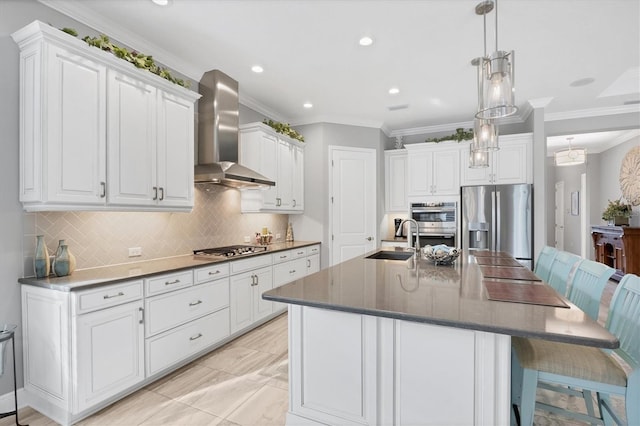 kitchen with stainless steel appliances, a kitchen island with sink, sink, wall chimney range hood, and white cabinetry