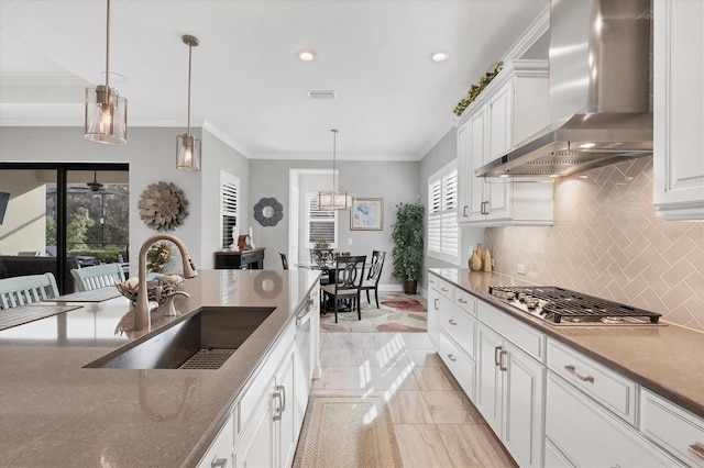 kitchen with pendant lighting, stainless steel gas stovetop, backsplash, sink, and wall chimney exhaust hood