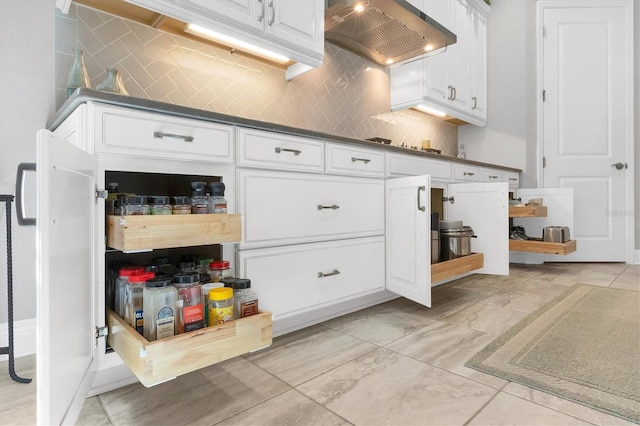 kitchen featuring decorative backsplash, white cabinetry, and wall chimney range hood