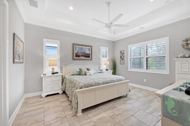 bedroom featuring ceiling fan, multiple windows, and a tray ceiling