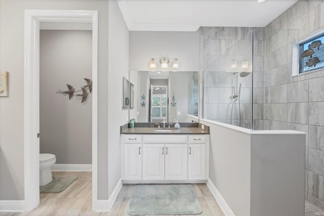 bathroom featuring tiled shower, vanity, toilet, and crown molding