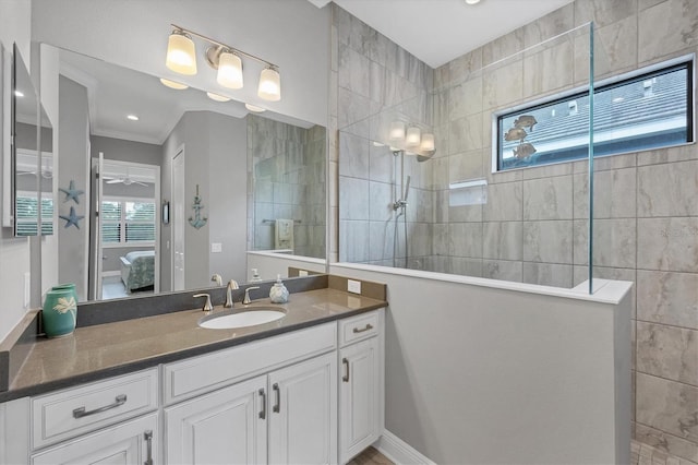 bathroom featuring vanity, ceiling fan, ornamental molding, and tiled shower