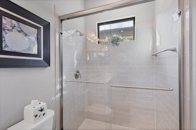 bathroom featuring toilet and a shower with shower door