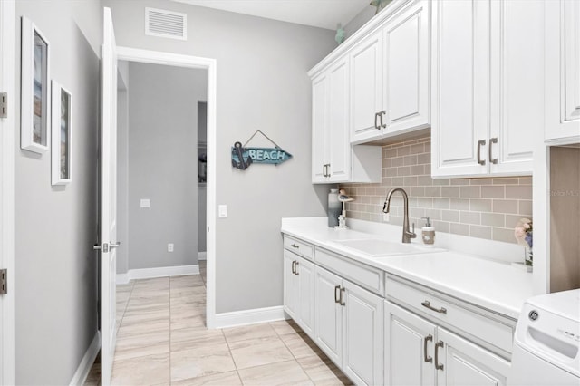 kitchen with white cabinets, sink, light tile patterned floors, tasteful backsplash, and washer / clothes dryer