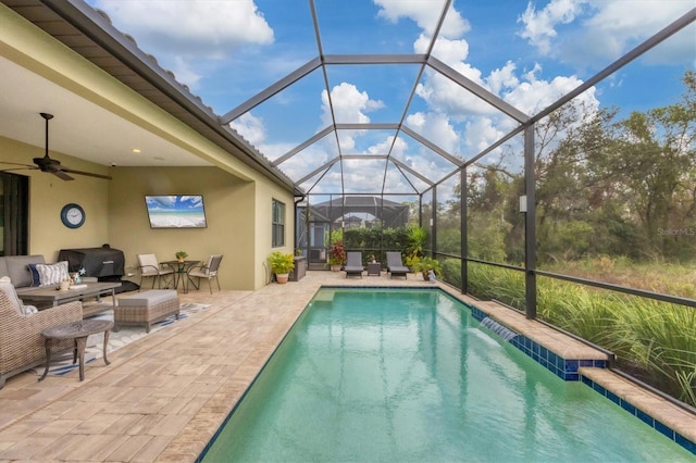 view of swimming pool with glass enclosure, ceiling fan, a patio, and an outdoor hangout area