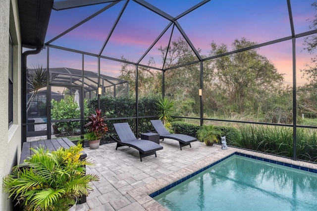 pool at dusk featuring a patio area and glass enclosure