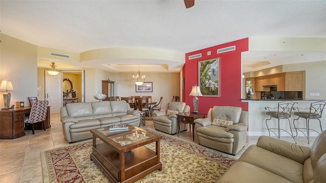 living room featuring light tile patterned floors, a textured ceiling, a tray ceiling, and an inviting chandelier