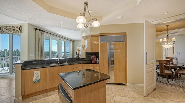 kitchen with pendant lighting, paneled refrigerator, a textured ceiling, and a chandelier