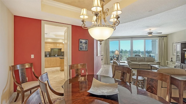 tiled dining area with a raised ceiling, crown molding, ceiling fan with notable chandelier, and a textured ceiling