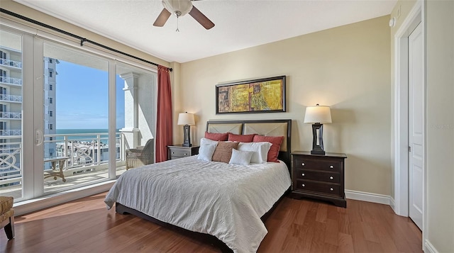 bedroom featuring ceiling fan, dark hardwood / wood-style flooring, and a water view