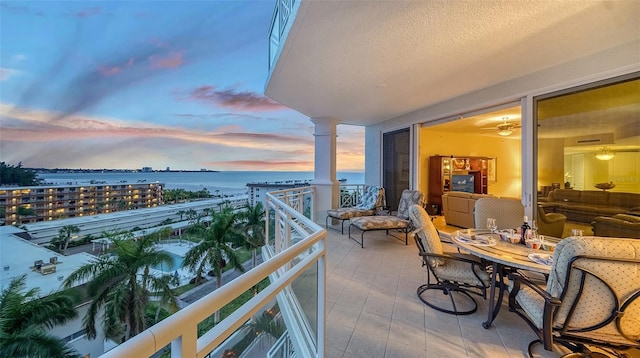 balcony at dusk featuring a water view