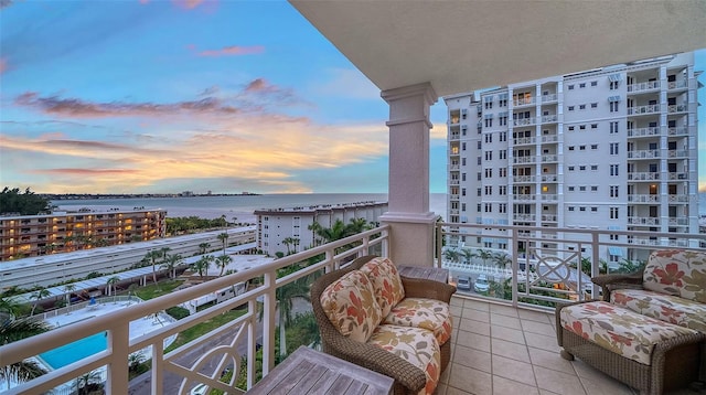 balcony at dusk featuring a water view