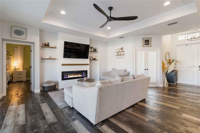 living room featuring ornamental molding, a raised ceiling, ceiling fan, and dark wood-type flooring