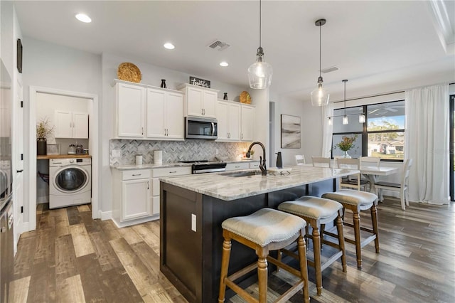 kitchen with white cabinets, stainless steel appliances, and washer / dryer