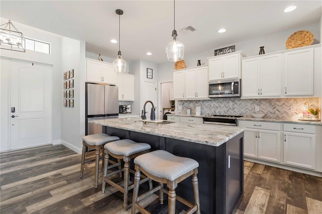 kitchen featuring white cabinetry, pendant lighting, an island with sink, and stainless steel appliances