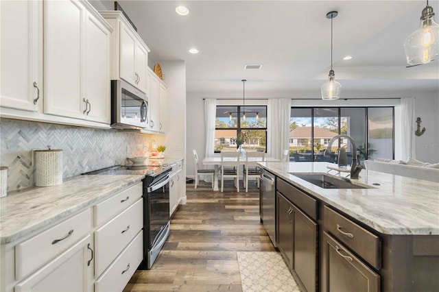 kitchen with sink, dark wood-type flooring, pendant lighting, white cabinets, and appliances with stainless steel finishes