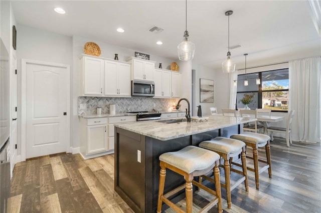 kitchen featuring white cabinets, stainless steel appliances, a kitchen island with sink, and sink