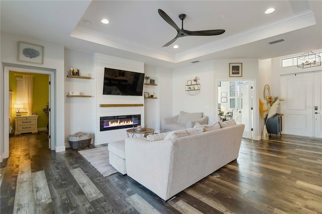 living room with a tray ceiling, ceiling fan, dark hardwood / wood-style flooring, and crown molding