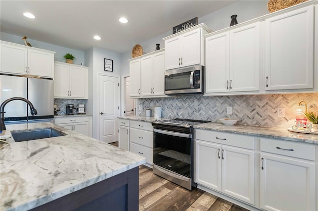 kitchen featuring sink, tasteful backsplash, dark hardwood / wood-style floors, white cabinets, and appliances with stainless steel finishes