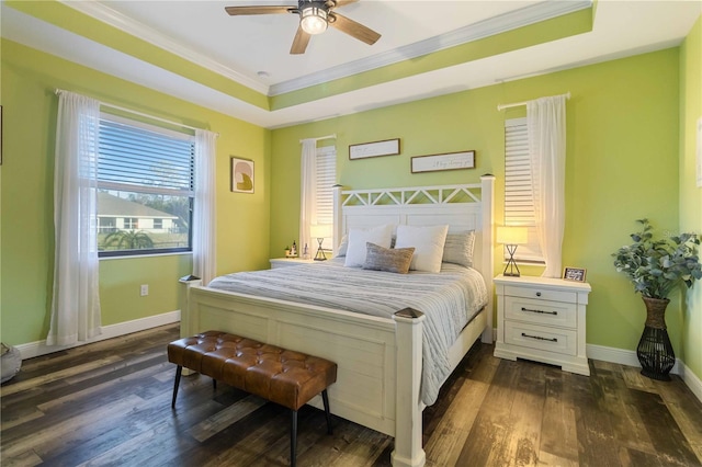 bedroom featuring ceiling fan, ornamental molding, dark wood-type flooring, and a tray ceiling