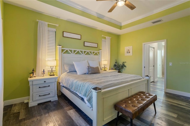 bedroom featuring a tray ceiling, ceiling fan, dark wood-type flooring, and ornamental molding