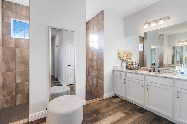 bathroom featuring hardwood / wood-style floors, vanity, and a tile shower