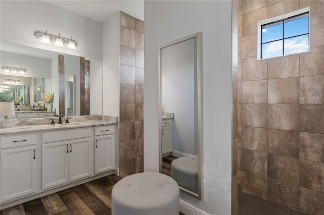 bathroom featuring vanity, wood-type flooring, and tiled shower