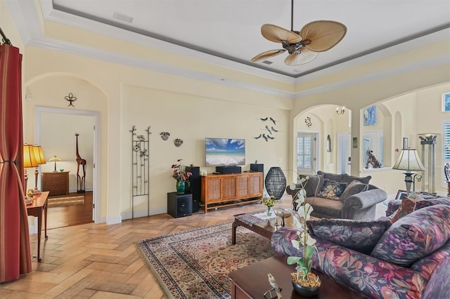 living room featuring light parquet flooring, a raised ceiling, ceiling fan, and crown molding