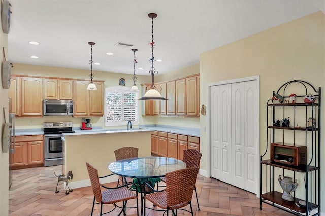 kitchen with light brown cabinets, hanging light fixtures, appliances with stainless steel finishes, and light parquet floors