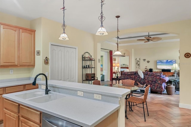 kitchen featuring light brown cabinets, sink, stainless steel dishwasher, ceiling fan, and an island with sink