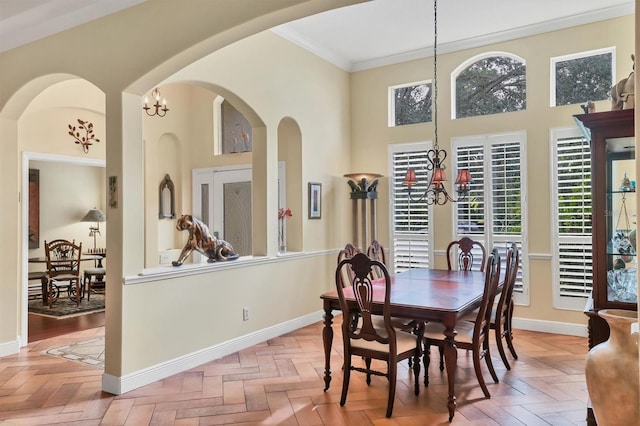 dining area with light parquet floors, crown molding, and an inviting chandelier