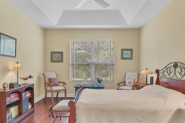 bedroom with a raised ceiling, multiple windows, ceiling fan, and hardwood / wood-style floors